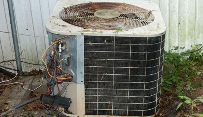 Old, rusty AC condenser with exposed electrical components