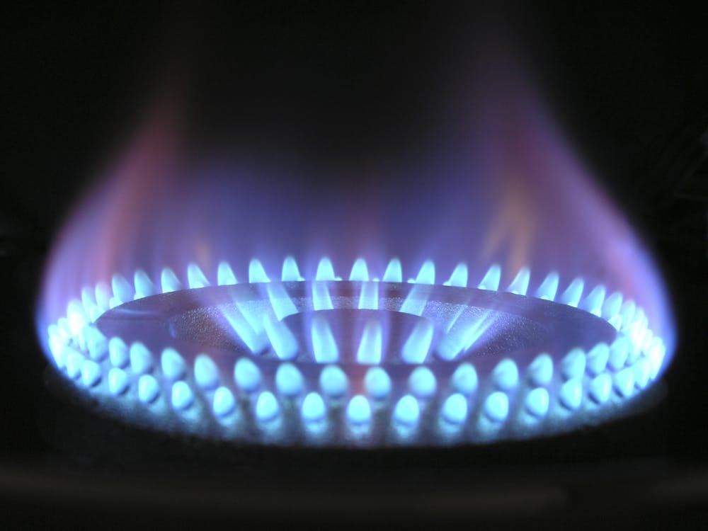 Close up image of natural gas stove burner glowing blue in dark room